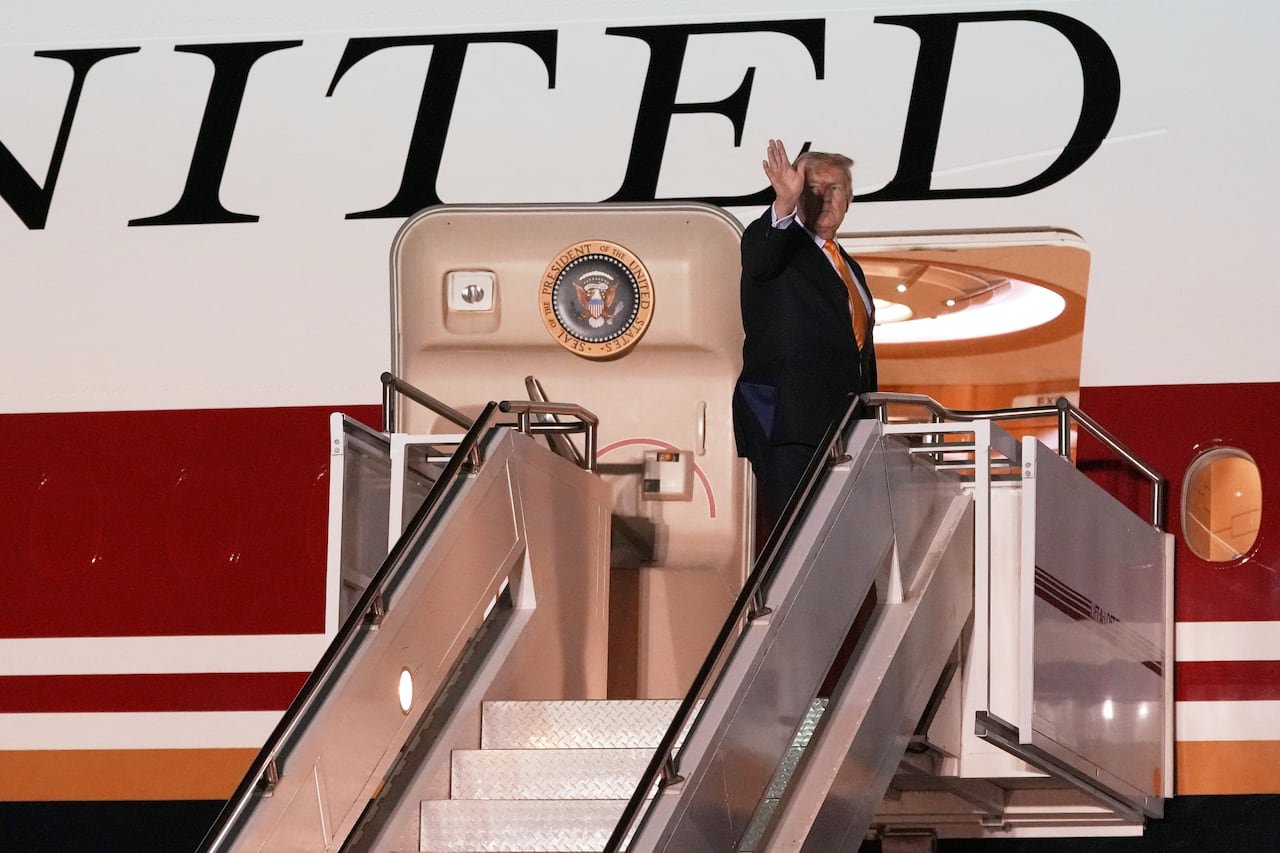 default-105 A man waves from the top of the staircase leading to an airplane.